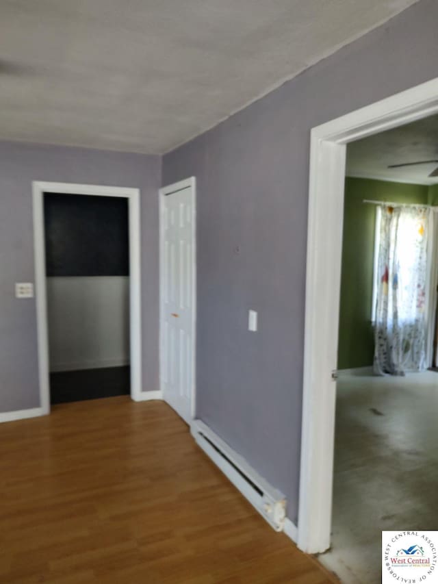 corridor featuring a baseboard radiator, wood finished floors, and baseboards