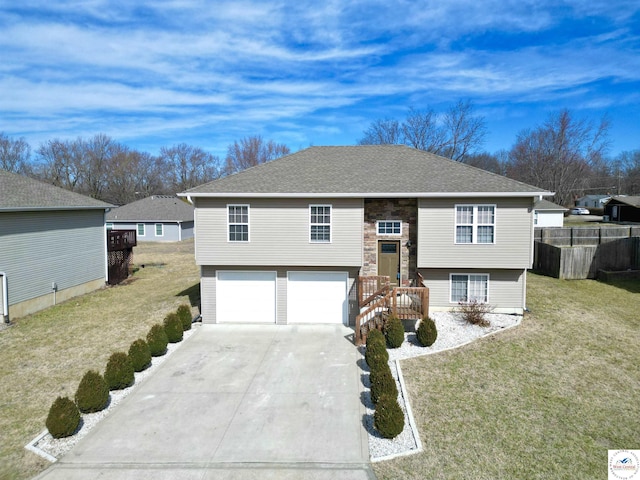 split foyer home with driveway, a garage, a shingled roof, fence, and a front yard