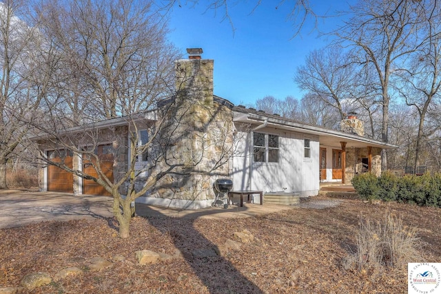 exterior space featuring covered porch, driveway, and a chimney