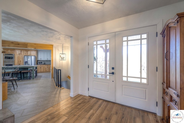 foyer entrance with a wealth of natural light, french doors, and light wood finished floors