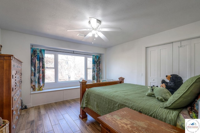 bedroom with visible vents, ceiling fan, wood finished floors, a closet, and a textured ceiling