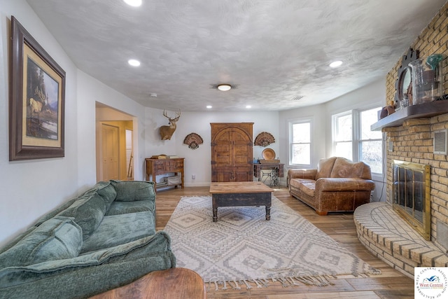 living area with recessed lighting, a brick fireplace, baseboards, and wood finished floors