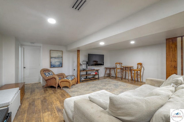 living room with recessed lighting, visible vents, and wood finished floors