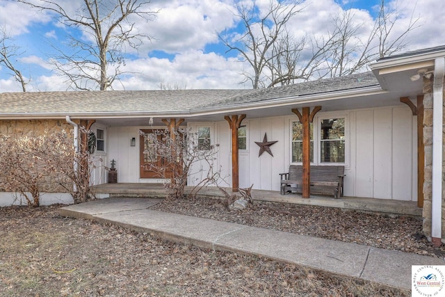 doorway to property featuring roof with shingles and covered porch