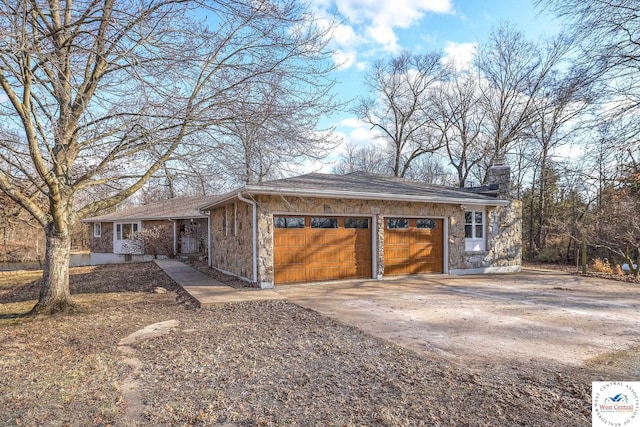 exterior space featuring concrete driveway, an attached garage, stone siding, and a chimney