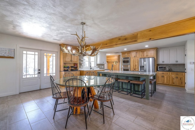 dining space featuring baseboards, a healthy amount of sunlight, a chandelier, and a toaster