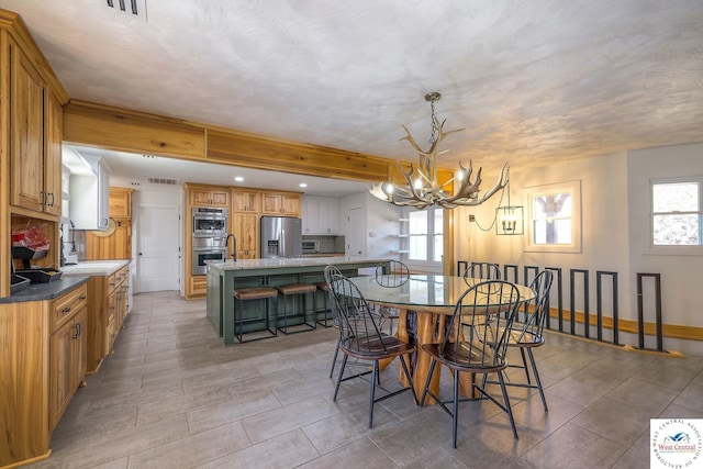 dining space featuring plenty of natural light, beamed ceiling, visible vents, and baseboards