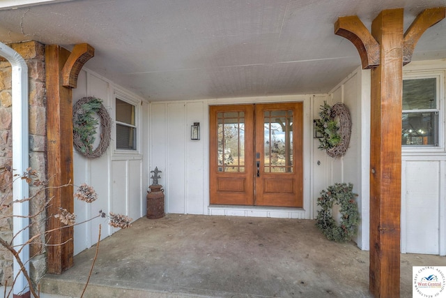 view of exterior entry featuring covered porch, french doors, and board and batten siding