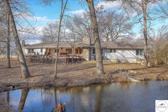 back of property with a water view and a chimney