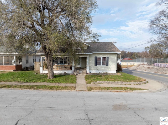 view of front of house featuring fence, a front lawn, and roof with shingles