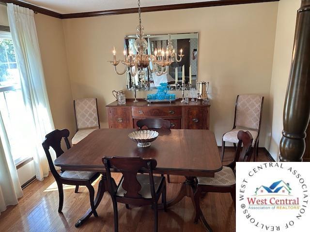 dining space with a notable chandelier, crown molding, and wood finished floors