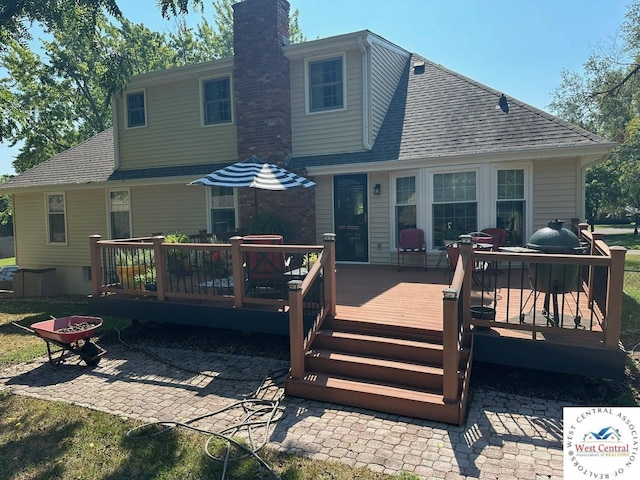 back of house featuring a chimney, roof with shingles, a patio, and a deck