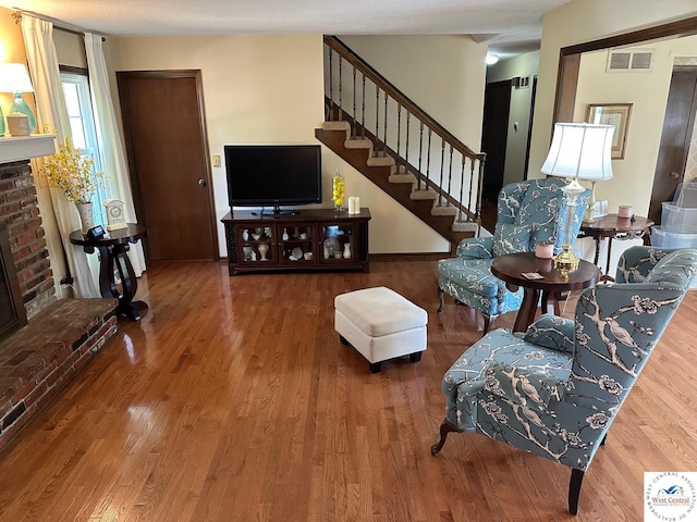 living area with stairs, a fireplace, wood finished floors, and visible vents