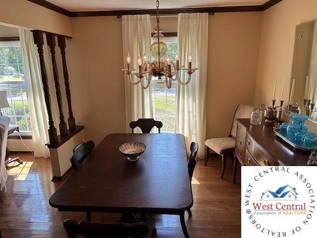 dining area featuring crown molding, a notable chandelier, and wood finished floors