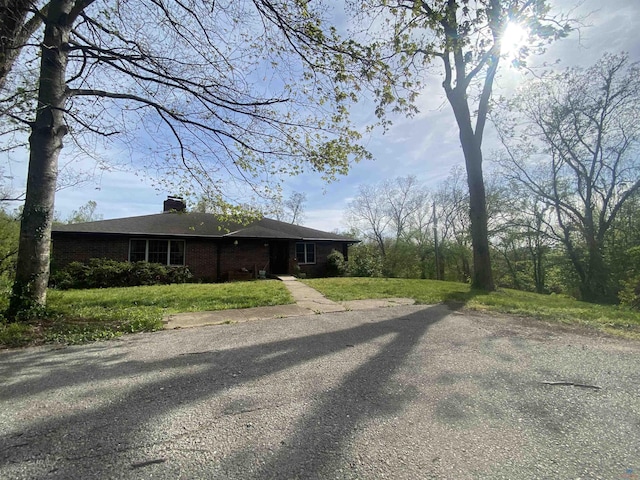 exterior space with brick siding, a lawn, and a chimney