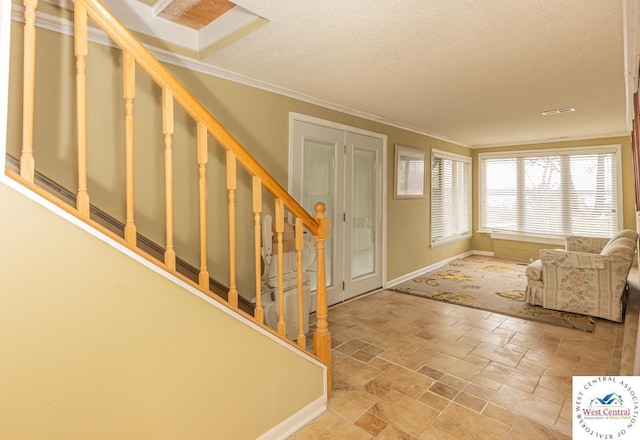 foyer entrance featuring stairway, a textured ceiling, baseboards, and ornamental molding