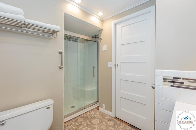 bathroom featuring toilet, a stall shower, and crown molding