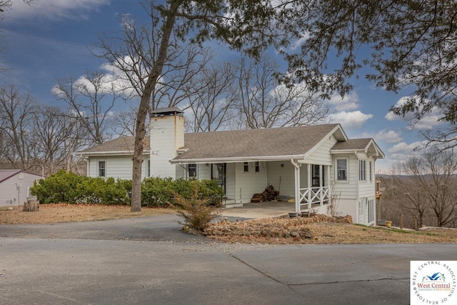 single story home featuring a porch, roof with shingles, and a chimney