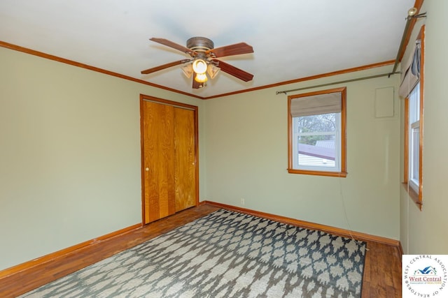 empty room featuring ceiling fan, wood finished floors, baseboards, and ornamental molding