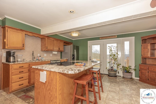 kitchen with a breakfast bar, stainless steel fridge with ice dispenser, a sink, crown molding, and a center island