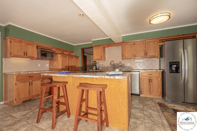 kitchen featuring a breakfast bar, ornamental molding, tasteful backsplash, a center island, and stainless steel appliances