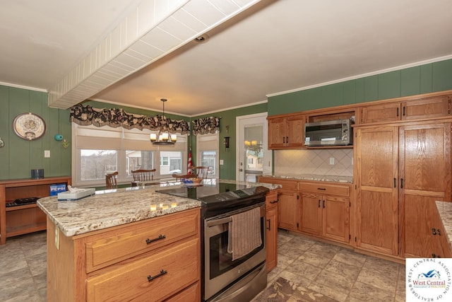 kitchen with ornamental molding, stainless steel appliances, tasteful backsplash, brown cabinets, and a chandelier