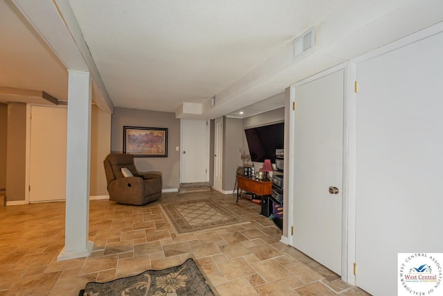 living area with visible vents, baseboards, and stone finish floor