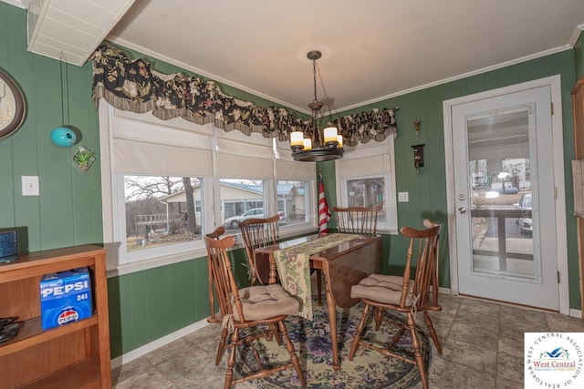 dining area with an inviting chandelier, a decorative wall, and ornamental molding