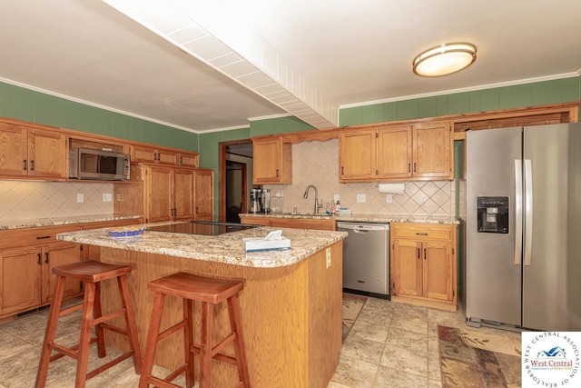 kitchen with a sink, tasteful backsplash, a center island, appliances with stainless steel finishes, and crown molding