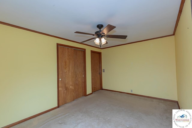 unfurnished bedroom featuring a ceiling fan, baseboards, ornamental molding, multiple closets, and carpet flooring