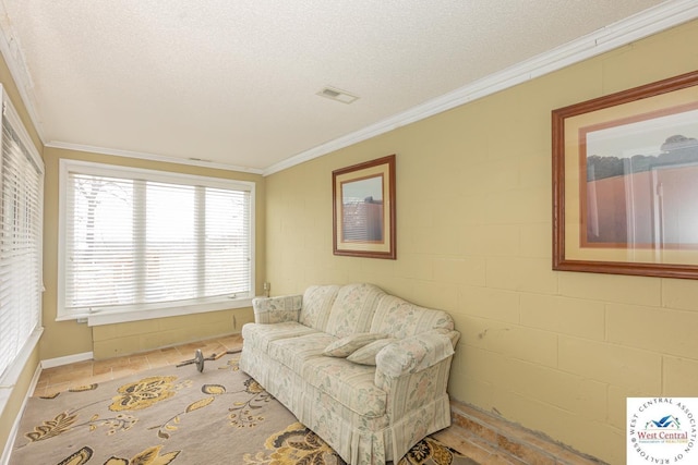 living area featuring a textured ceiling, concrete block wall, visible vents, and ornamental molding