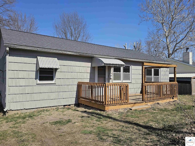 rear view of property with a wooden deck and roof with shingles