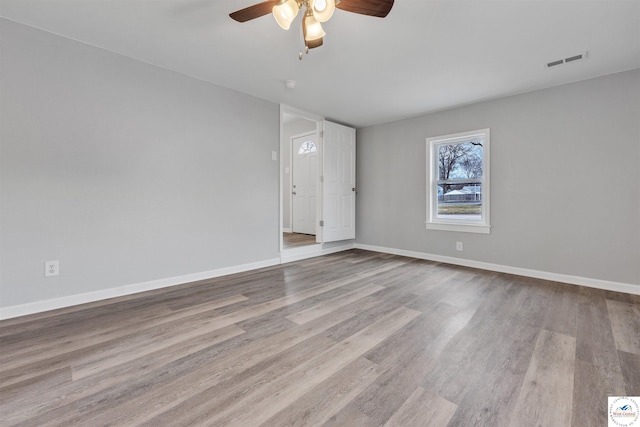 unfurnished room with a ceiling fan, baseboards, visible vents, and wood finished floors