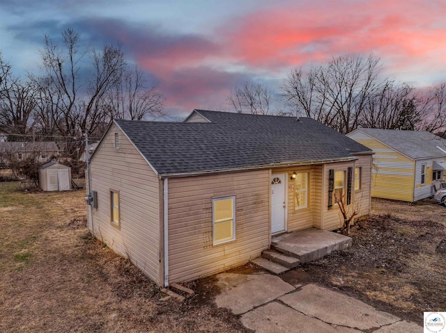 view of front of house with roof with shingles, an outdoor structure, and a shed