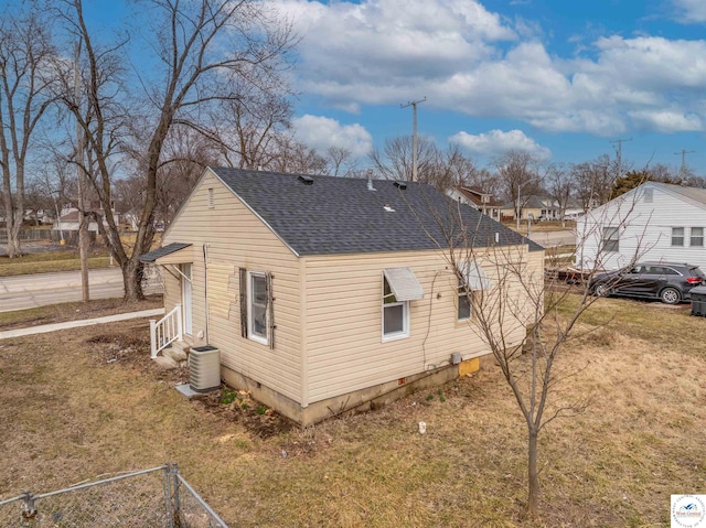 view of side of property with a shingled roof, a lawn, crawl space, central AC, and fence