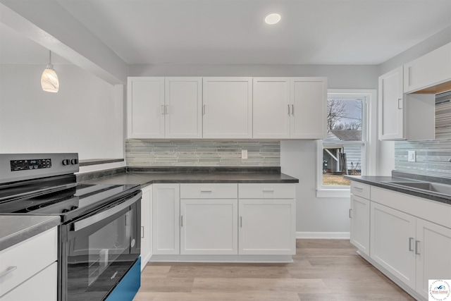 kitchen with a sink, white cabinets, light wood-type flooring, stainless steel electric range, and dark countertops