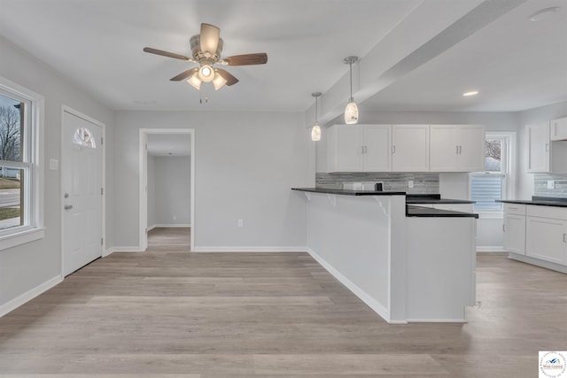 kitchen with light wood-type flooring, dark countertops, and white cabinetry