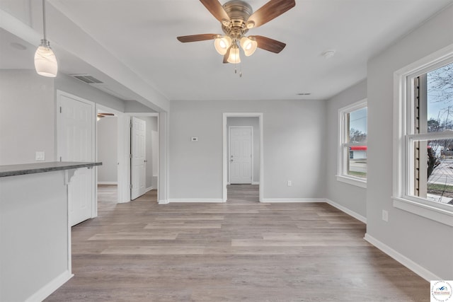 unfurnished living room featuring light wood finished floors, baseboards, visible vents, and ceiling fan