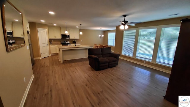 kitchen featuring pendant lighting, stainless steel appliances, light countertops, open floor plan, and white cabinetry