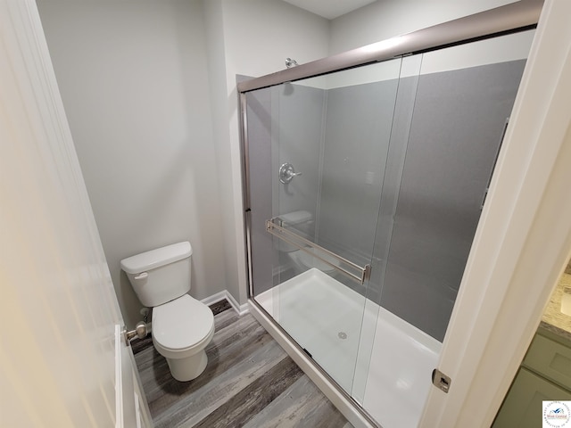 full bathroom with baseboards, a shower stall, toilet, and wood finished floors