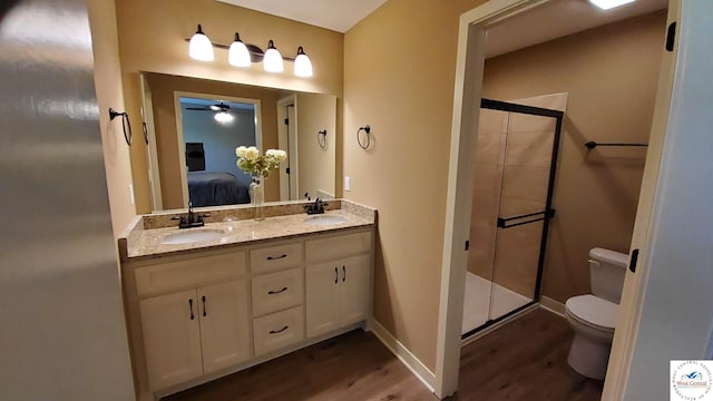 ensuite bathroom featuring toilet, a shower stall, a sink, and wood finished floors