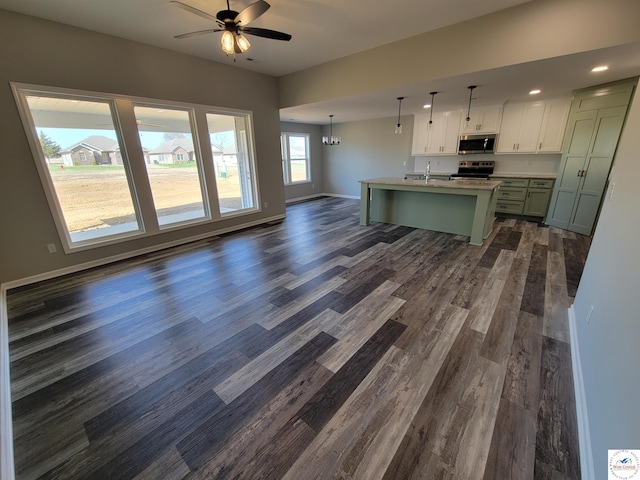 kitchen with appliances with stainless steel finishes, open floor plan, decorative light fixtures, a kitchen island with sink, and light countertops