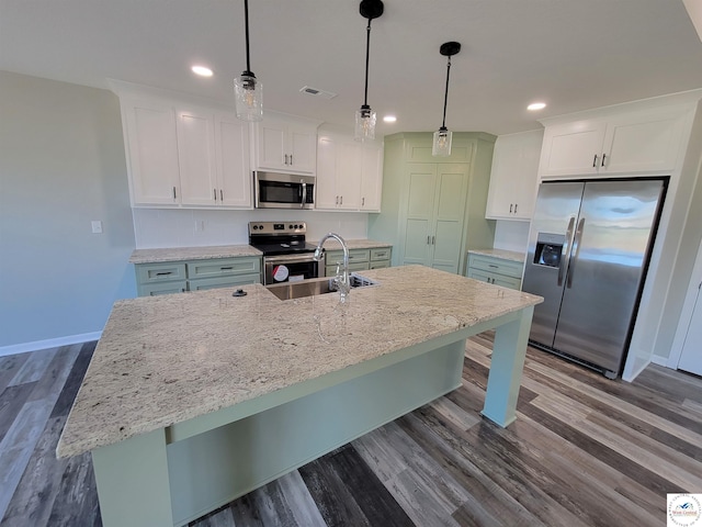 kitchen with stainless steel appliances, a sink, white cabinetry, an island with sink, and decorative light fixtures