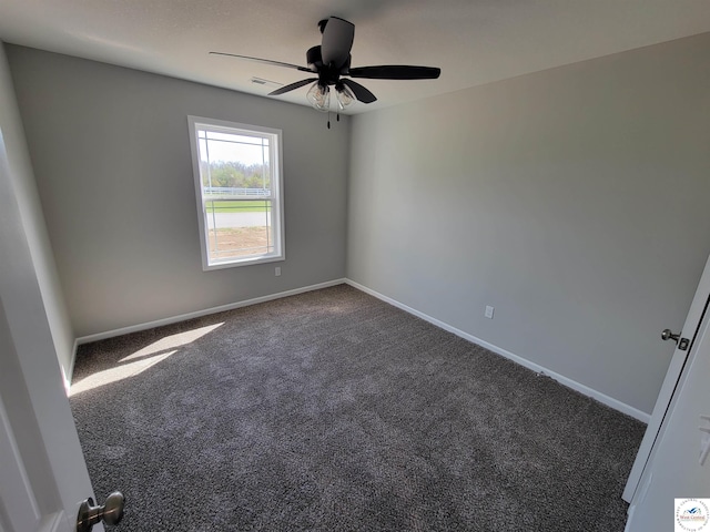 unfurnished room with visible vents, dark carpet, baseboards, and ceiling fan