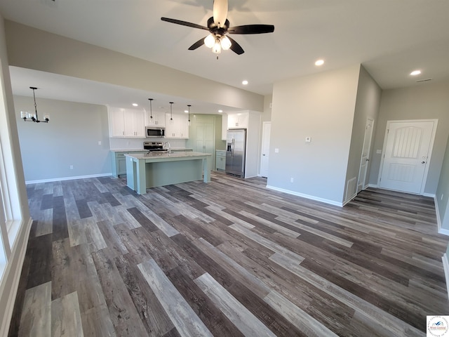 kitchen with a kitchen island with sink, appliances with stainless steel finishes, light countertops, and pendant lighting