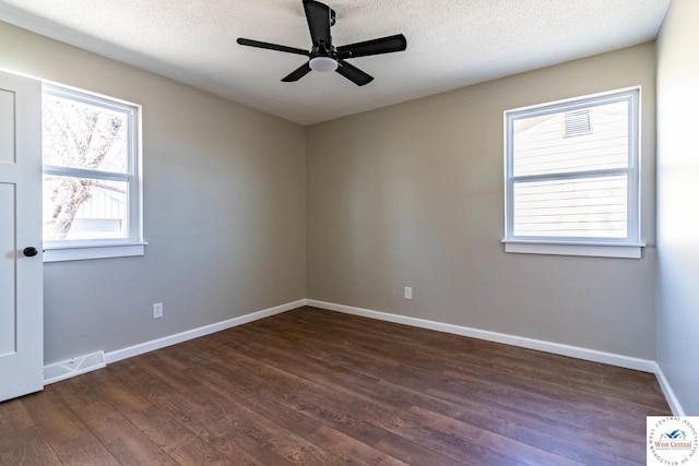 unfurnished room with visible vents, a textured ceiling, dark wood finished floors, baseboards, and ceiling fan