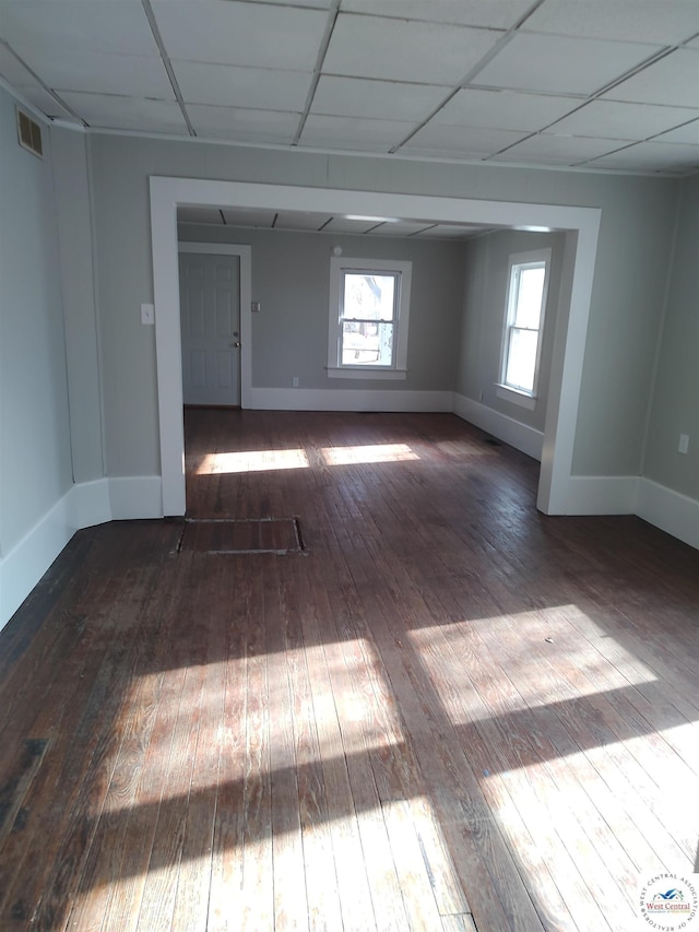 unfurnished room with a paneled ceiling, a healthy amount of sunlight, visible vents, and dark wood finished floors