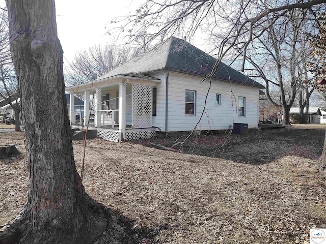 view of side of property featuring covered porch and roof with shingles