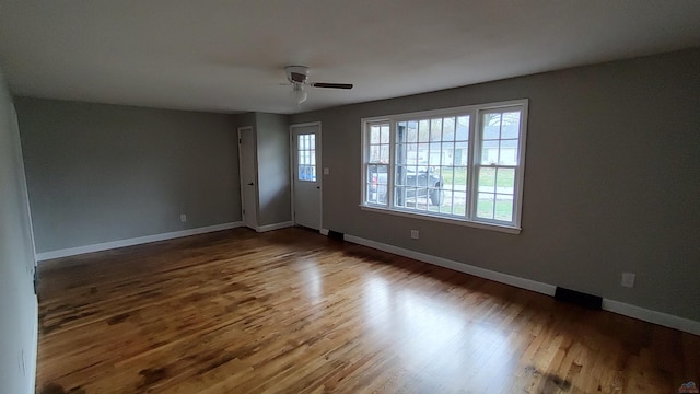 unfurnished room featuring a ceiling fan, baseboards, and wood finished floors