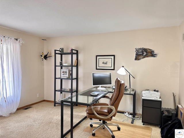 office space featuring a wealth of natural light, light colored carpet, visible vents, and baseboards